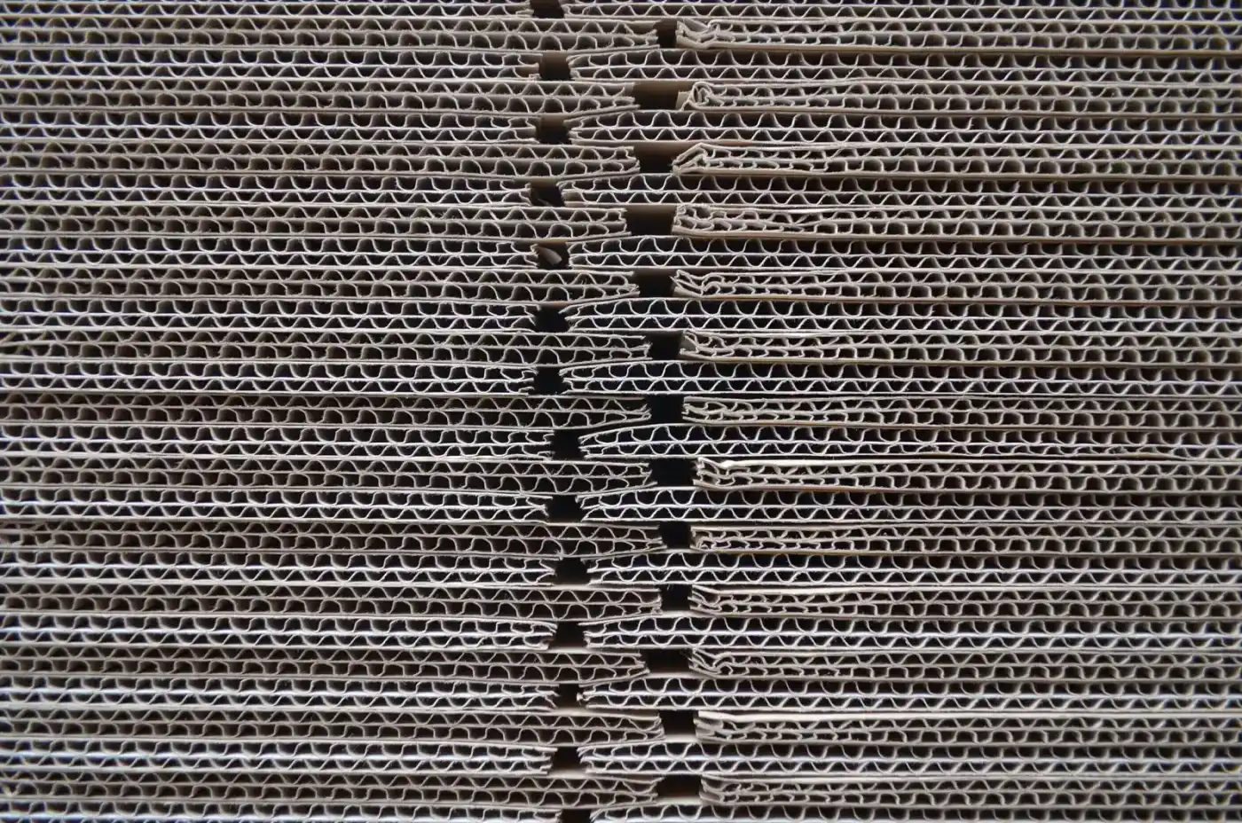 A close-up of stacked corrugated cardboard showing the wavy layer inside
