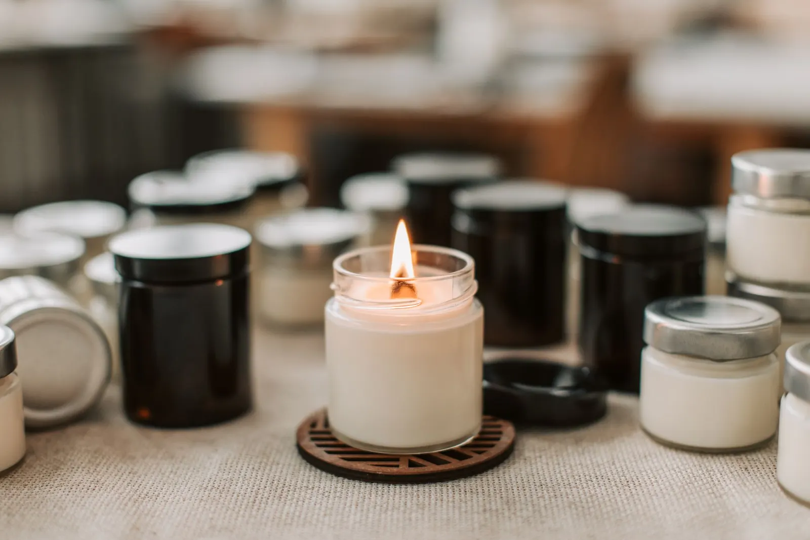 A white handmade candle burning among black and white candle jars