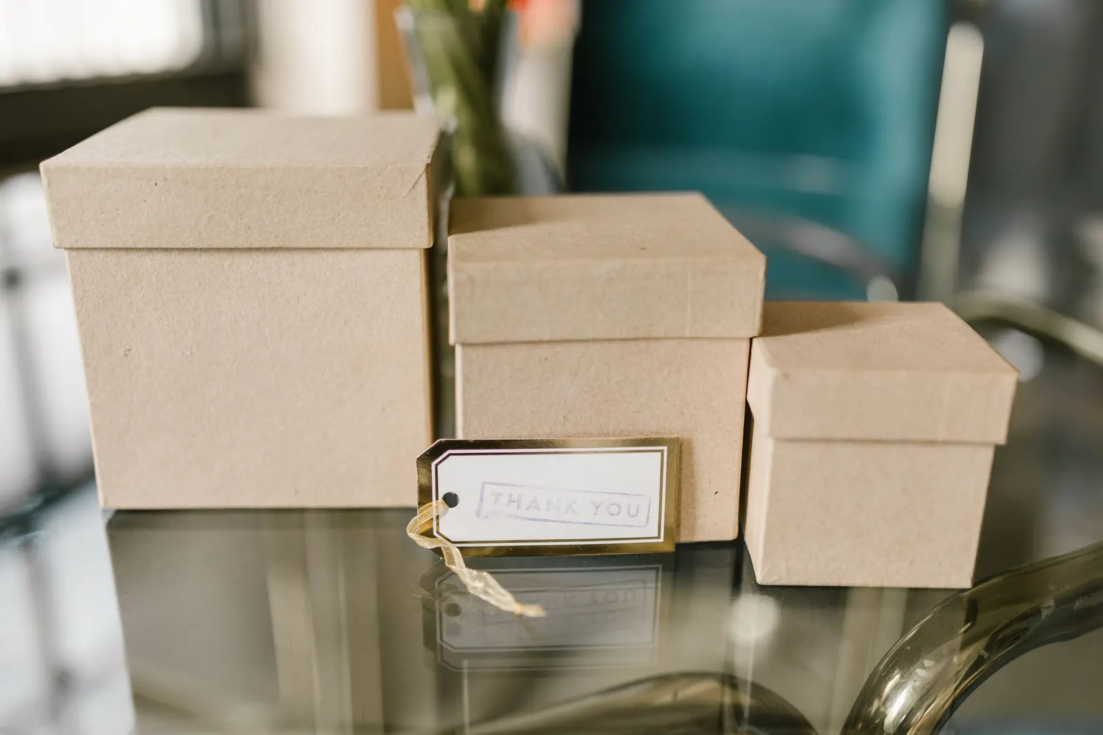 Three brown cardboard boxes with lids on a glass table