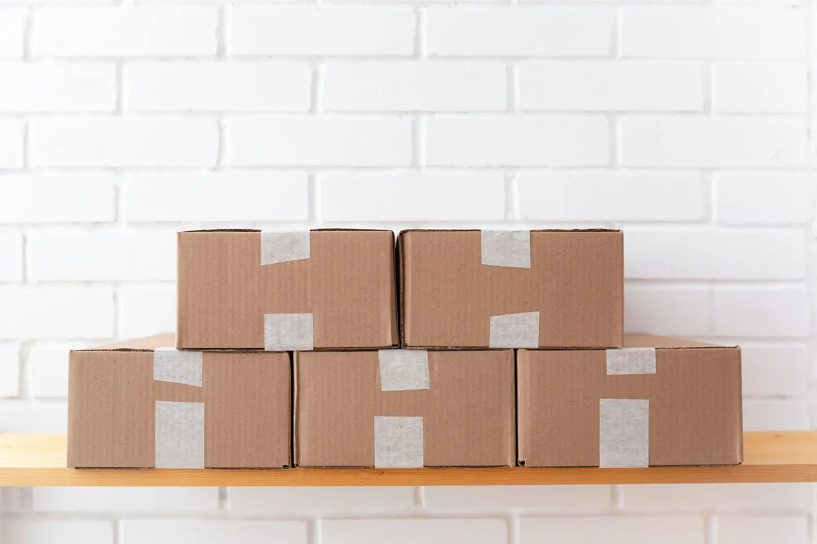 A neat stack of taped brown cardboard boxes on a wooden shelf